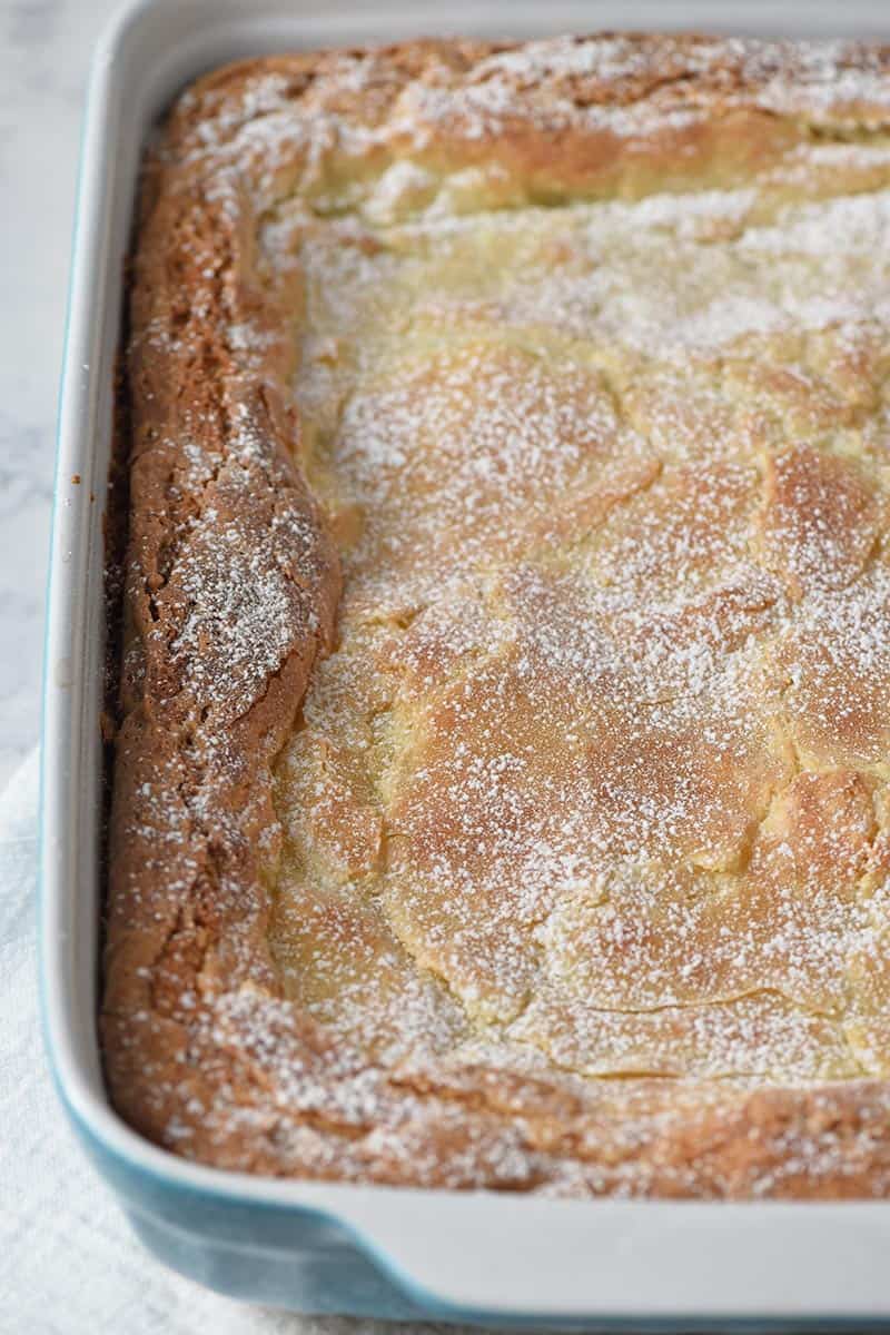 gooey butter cake baked in blue baking dish and dusted with powdered sugar