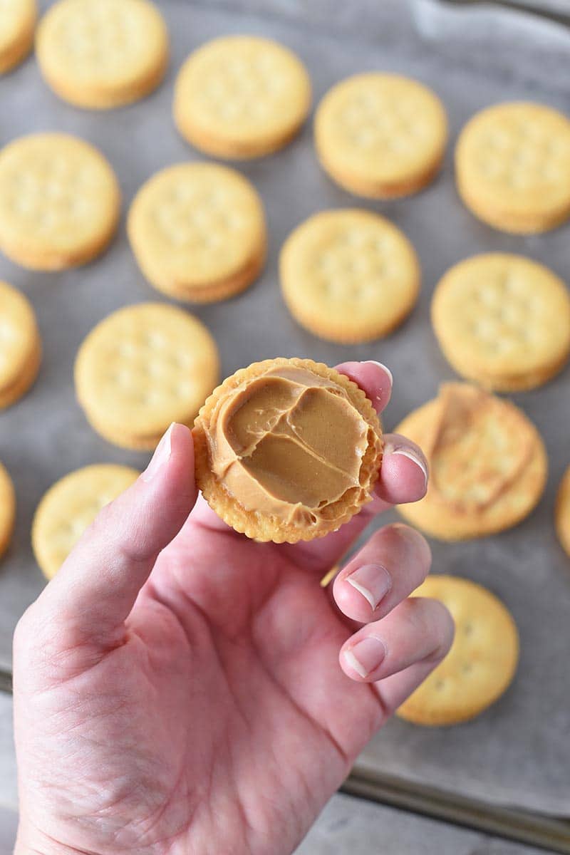 hand making peanut butter Ritz crackers with creamy peanut butter