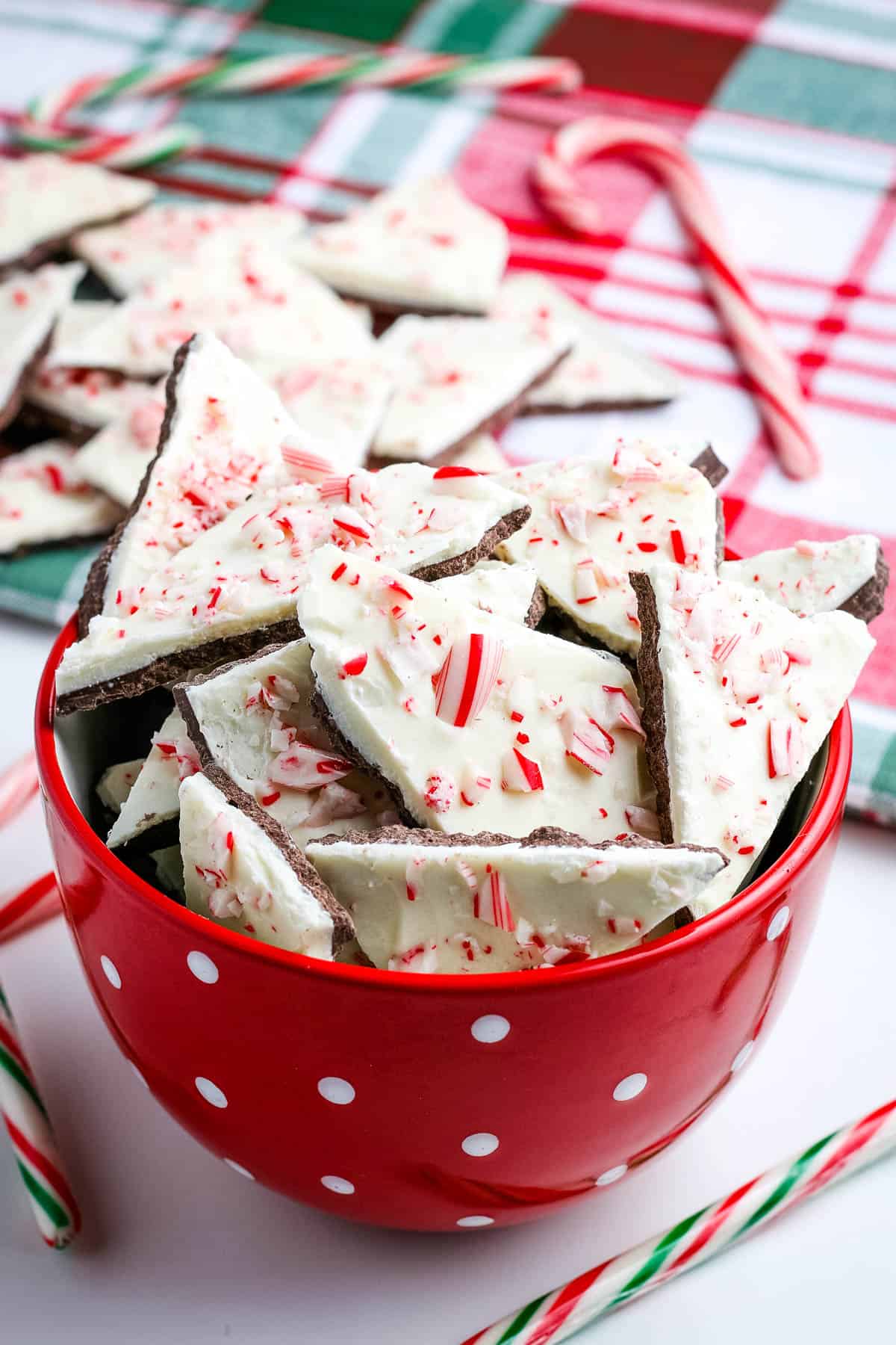 chocolate peppermint bark in red and white polka dot bowl with candy canes on white countertop