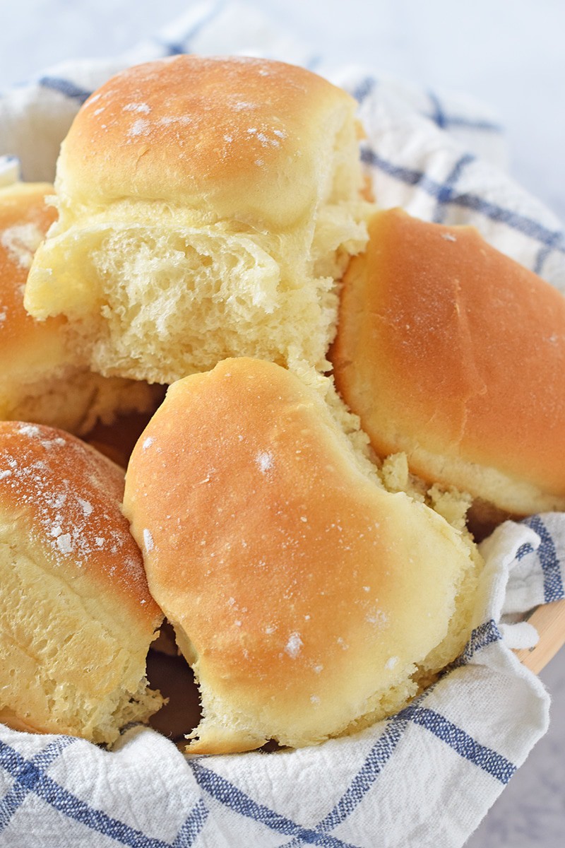 homemade dinner rolls from scratch in a bread roll basket with white and blue checked flour sack towel