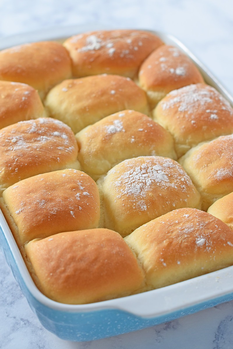 grandma's yeast rolls, puffy and pillowy bread rolls, in a blue baking dish