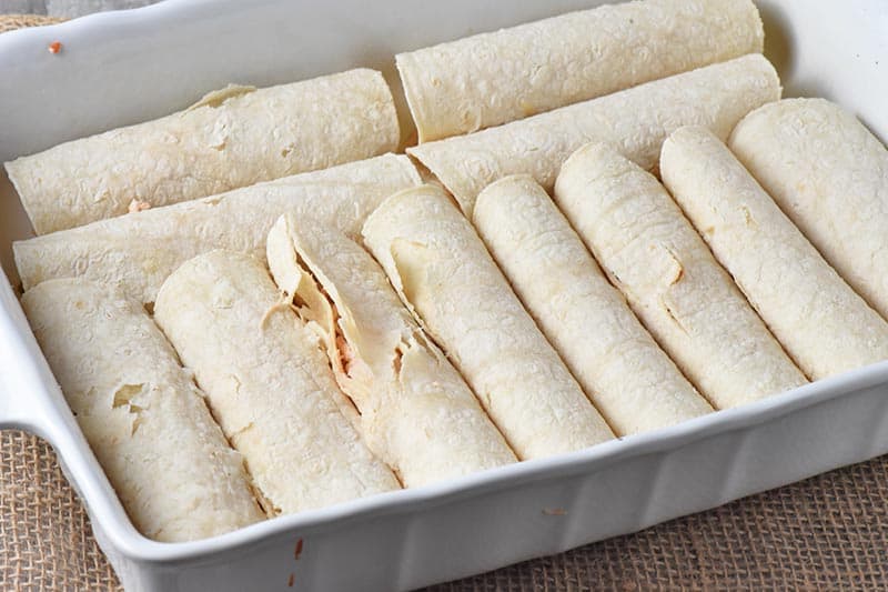 chicken enchiladas made with corn tortillas in white baking dish