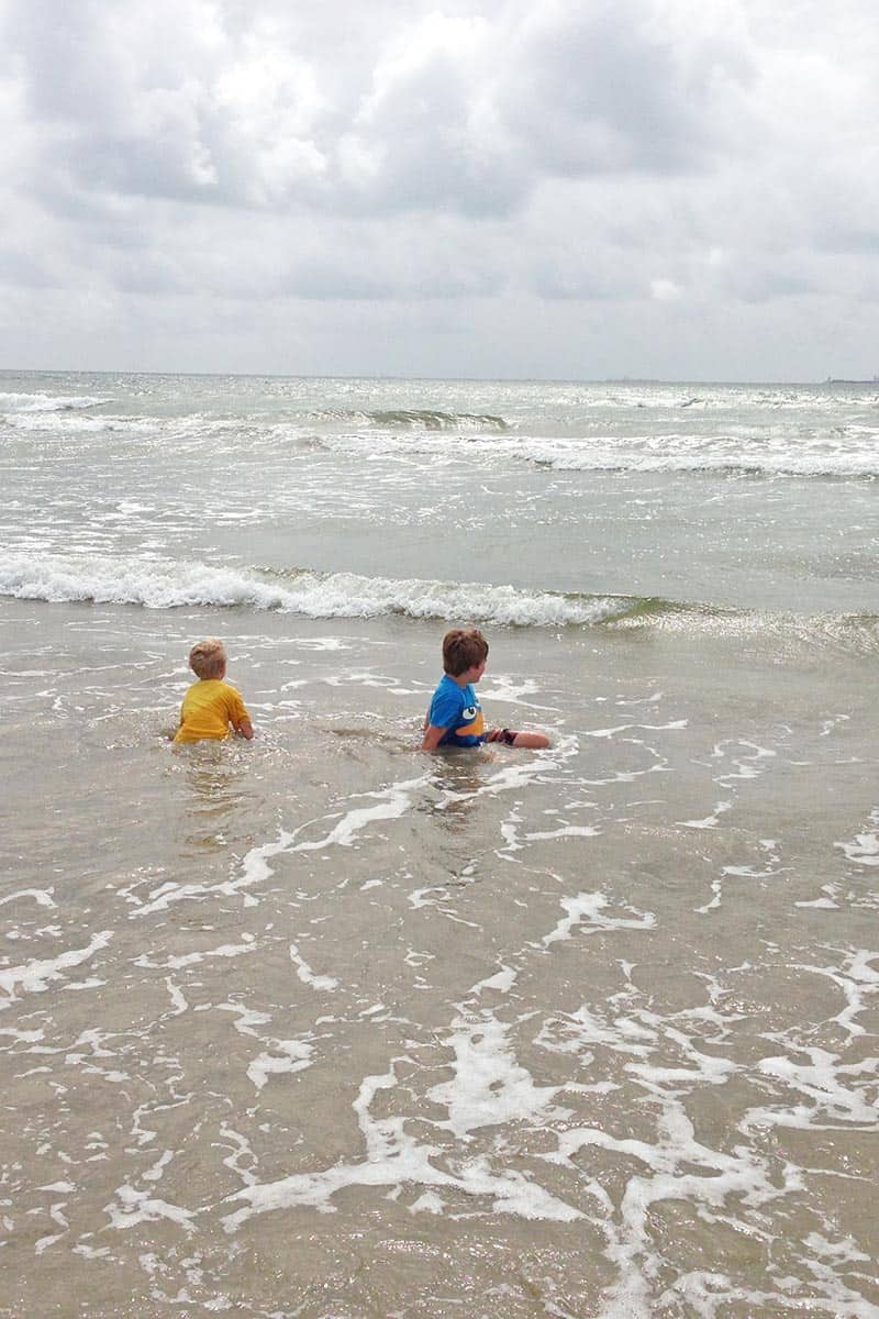 two boys playing in the waves and watching ships on San Jose Island beach