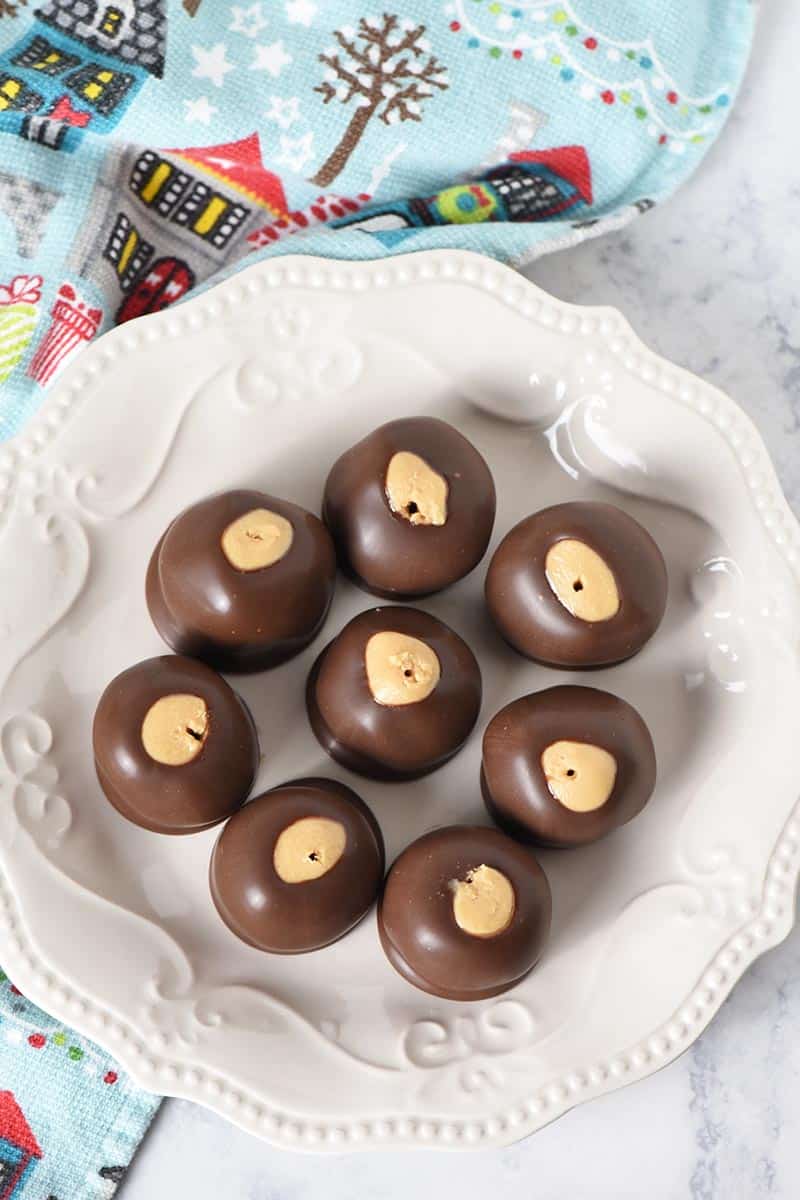 4 ingredient buckeyes peanut butter balls on ivory plate with blue Christmas kitchen towel