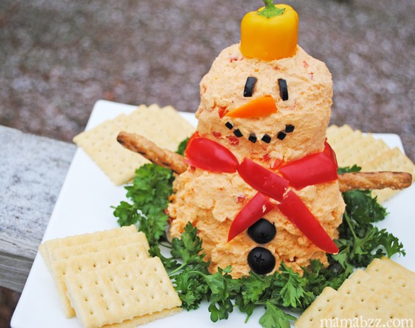 snowman pimento cheese ball on bed of parsley on white plate with crackers