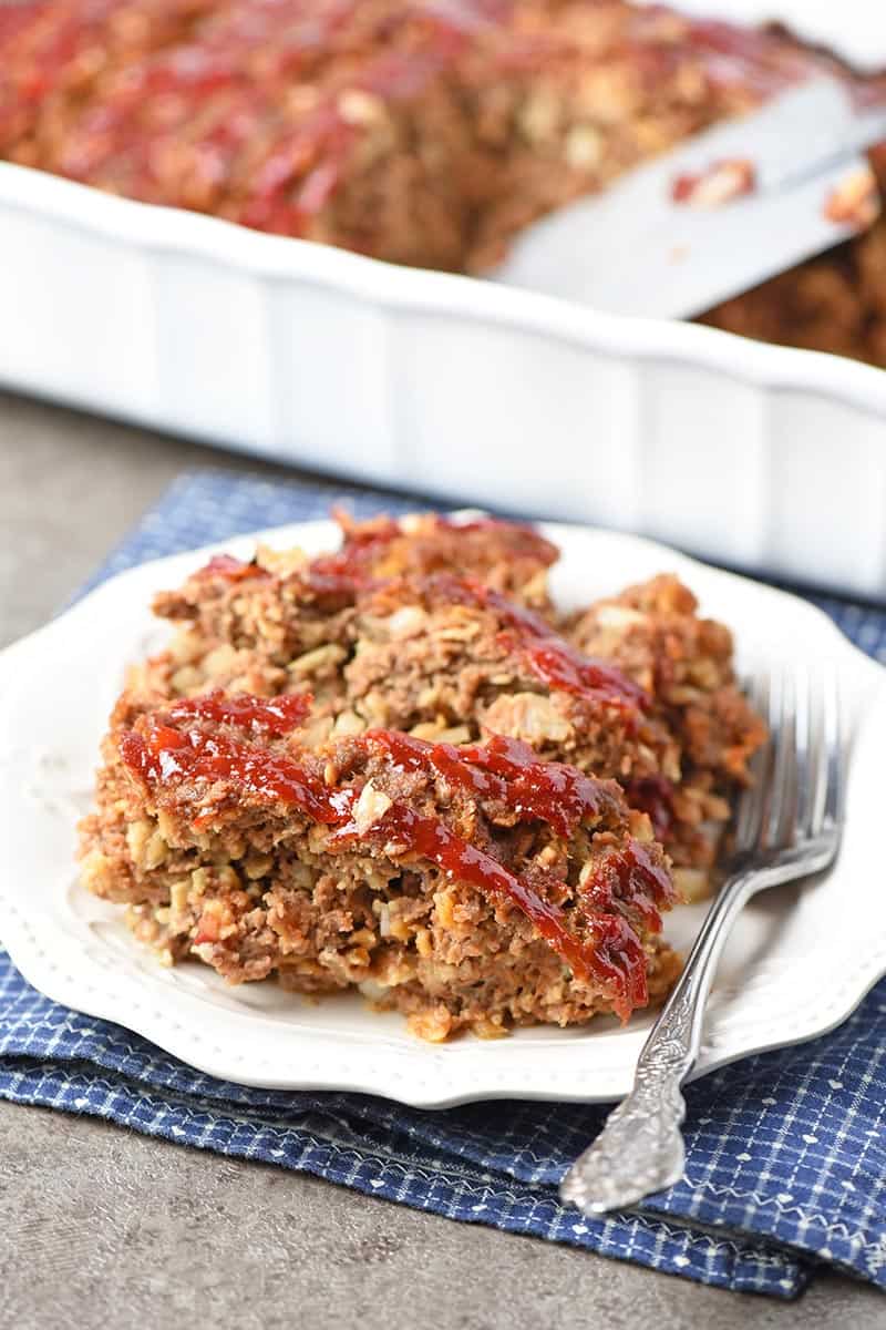 easy meatloaf recipe with oatmeal sliced on a pretty white plate ready to serve with a fork