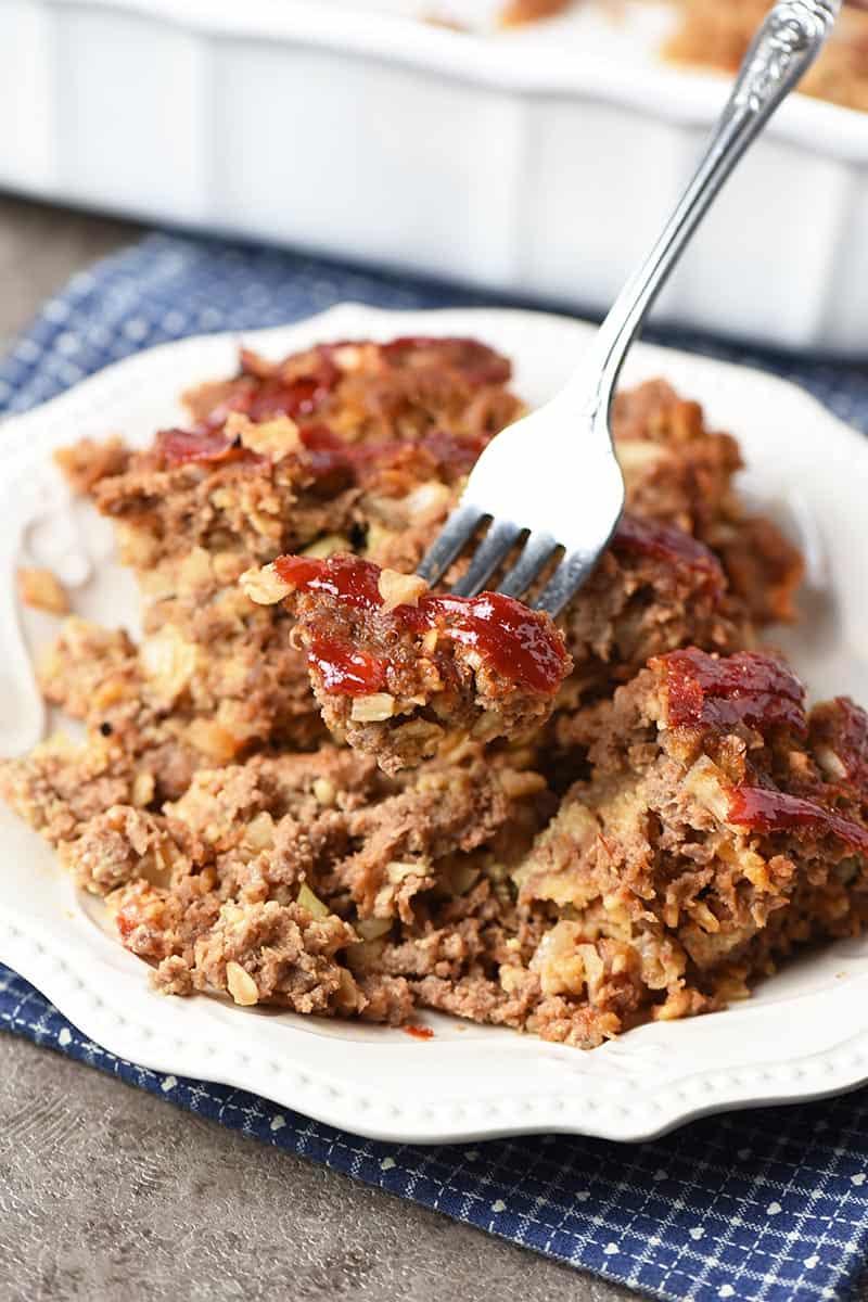 forked bite of meatloaf with oatmeal on white plate