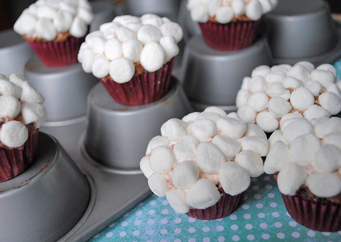 fluffy chocolate bunny tail cupcakes topped with mini marshmallows on muffin tin and teal and white polka dot paper