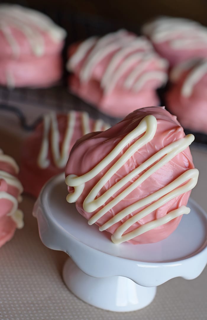 pink Valentine's Day Little Debbie cakes on white cupcake stand and tan countertop