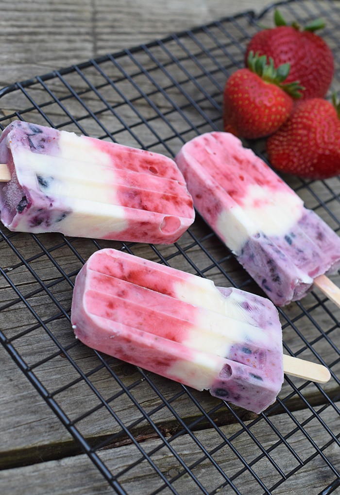 red white and blue pops on a wire rack with fresh berries