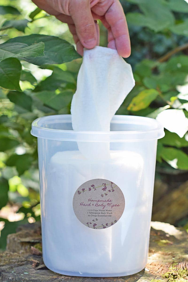 hand pulling out homemade camping body wipes from a plastic storage container