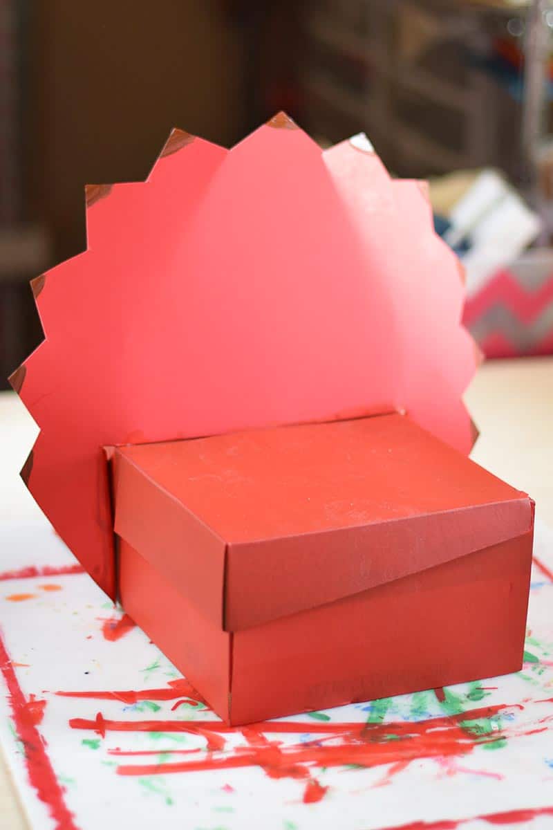 placing triceratops crest onto shoebox to make a homemade dinosaur Valentines box