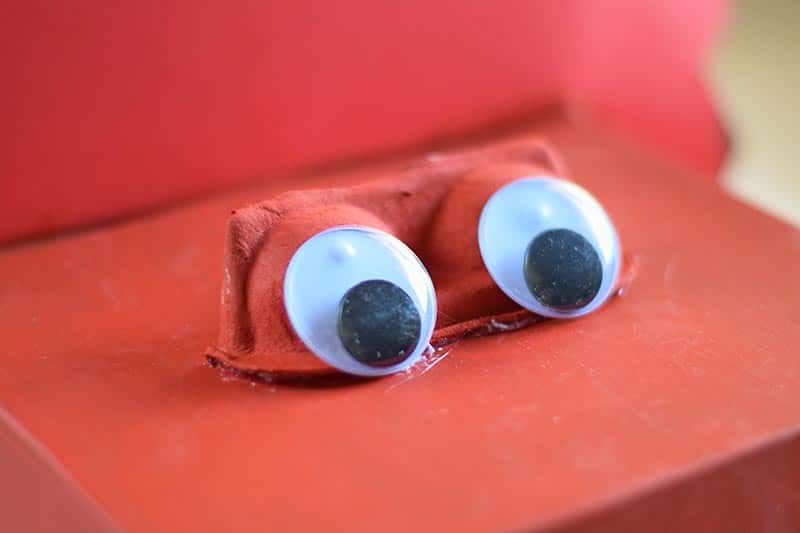 glueing googly eyes onto red dinosaur Valentine box