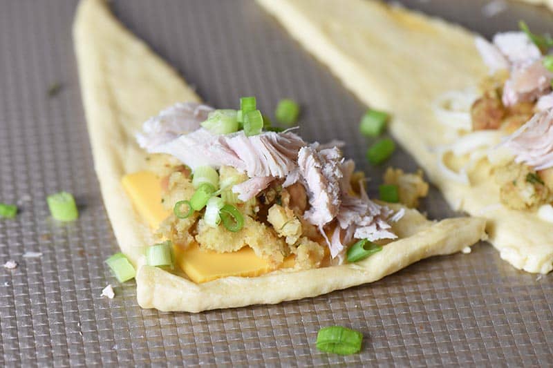 leftover turkey, stuffing, American cheese, and green onions being stuffed into a crescent roll for Thanksgiving appetizers