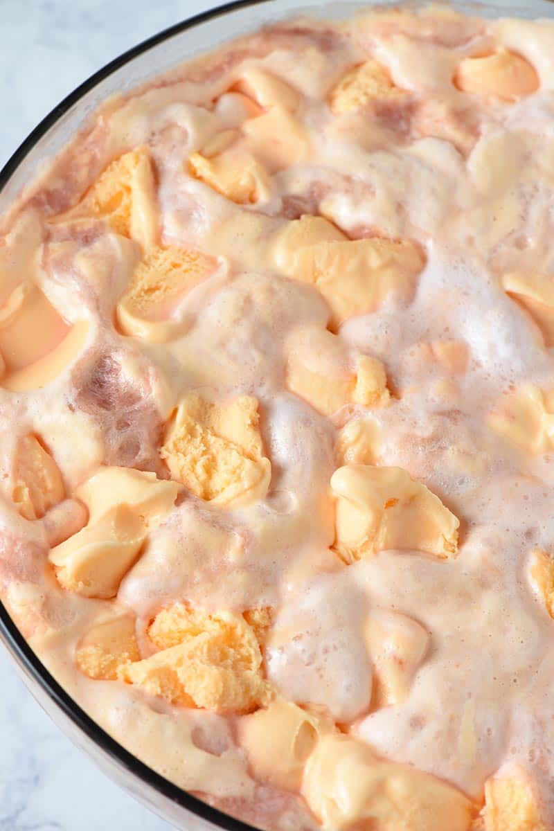 scooping plenty of orange sherbet onto top of sherbet punch in punch bowl