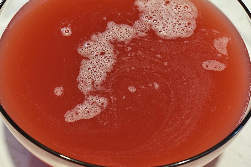 pouring juice for orange sherbet punch into large punch bowl