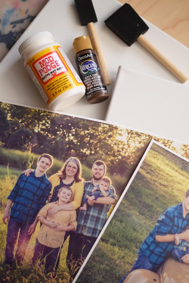 supplies for a photo transfer to canvas, including Mod Podge, acrylic paint, foam brushes, and family photos