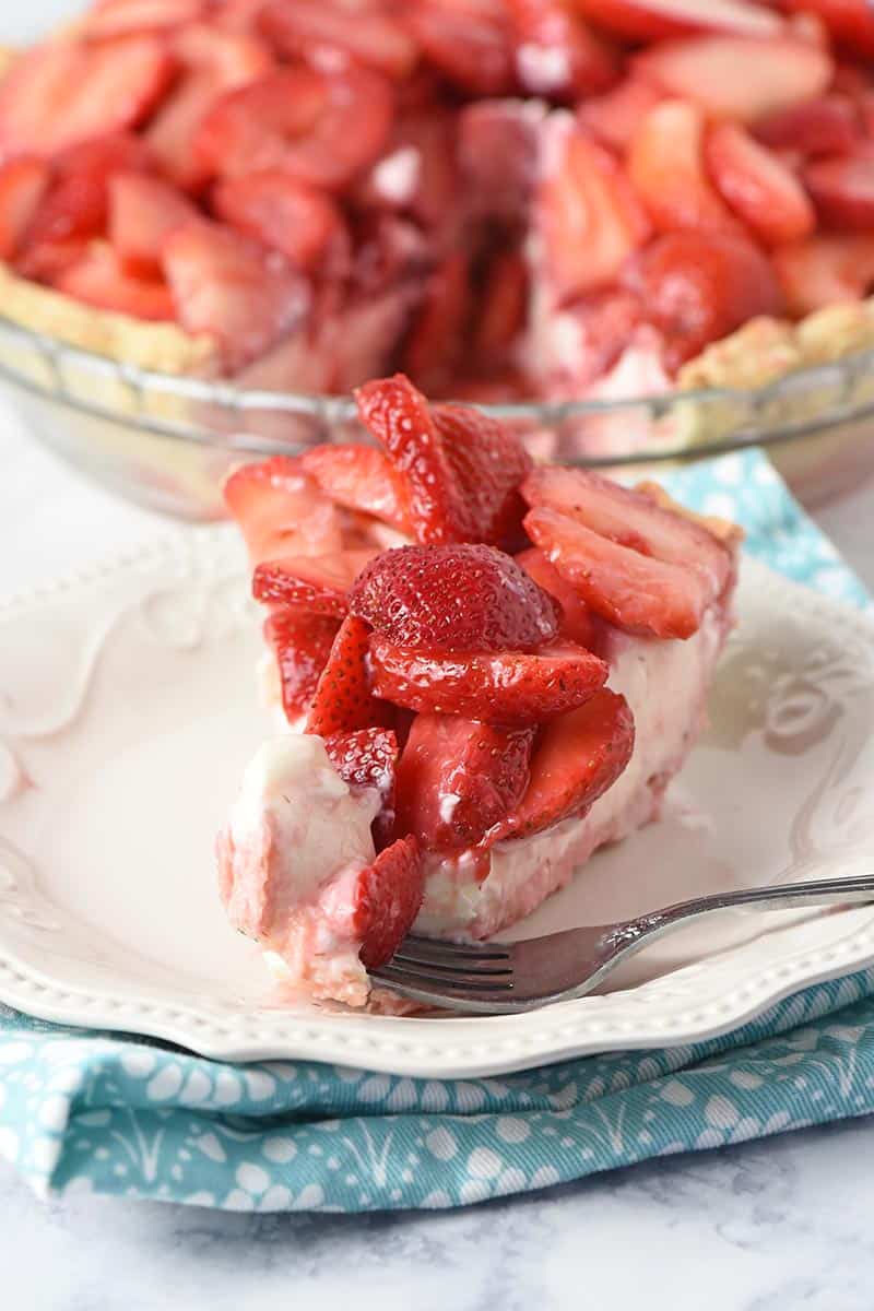 bite of strawberry cream pie on a fork with slice of pie on plate
