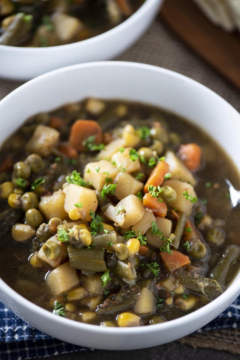 chunky vegetable soup in white soup bowl with spoon