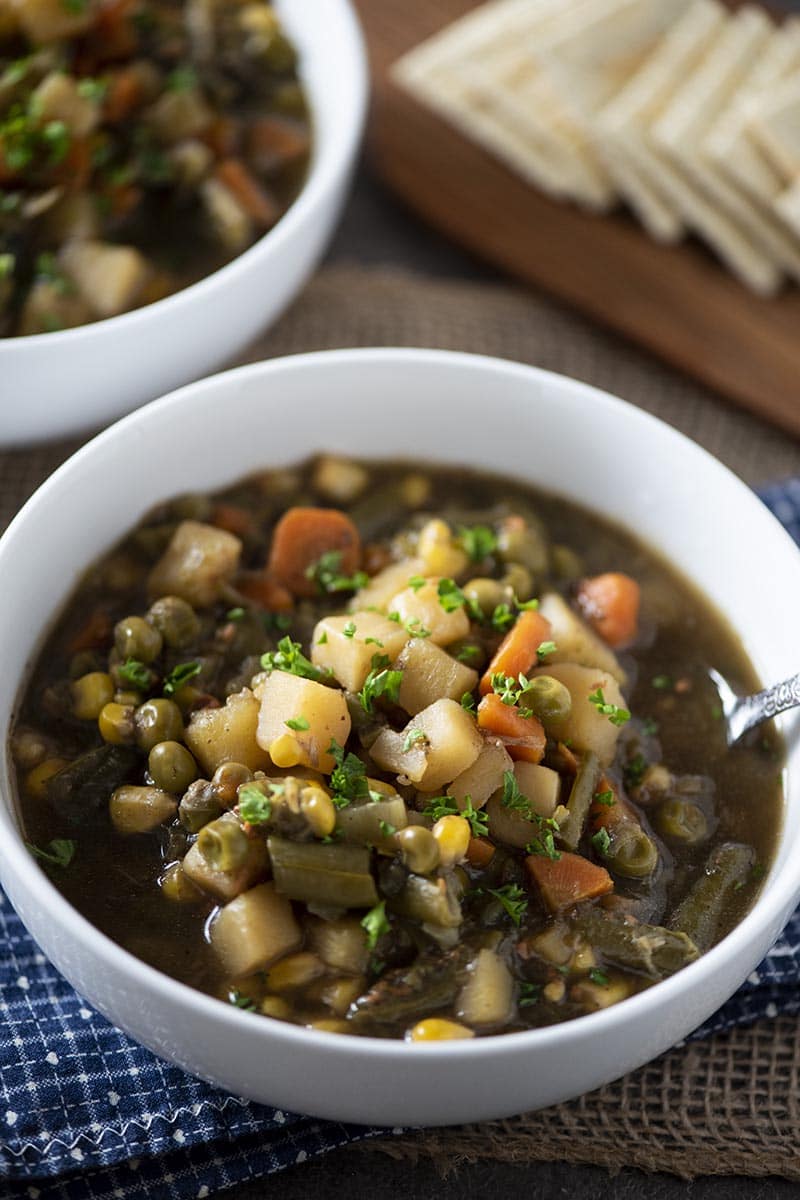 white bowl of Instant Pot vegetable soup with spoon and crackers