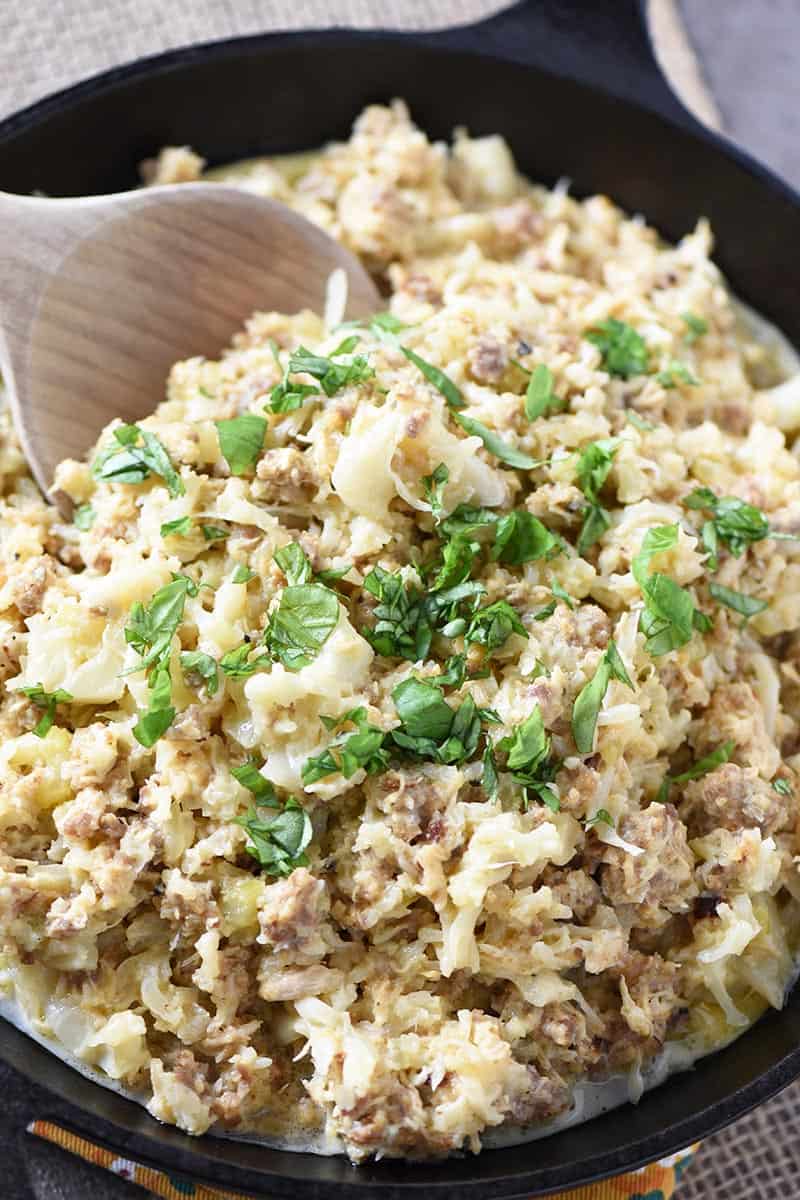 low carb cheesy chicken casserole in cast iron skillet with wooden spoon