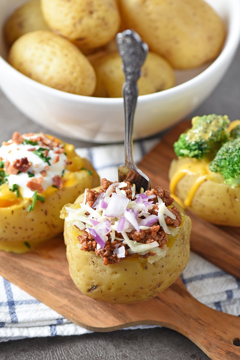 potato bar ideas, including sloppy joe meat and red onion, with fork on wood cutting board