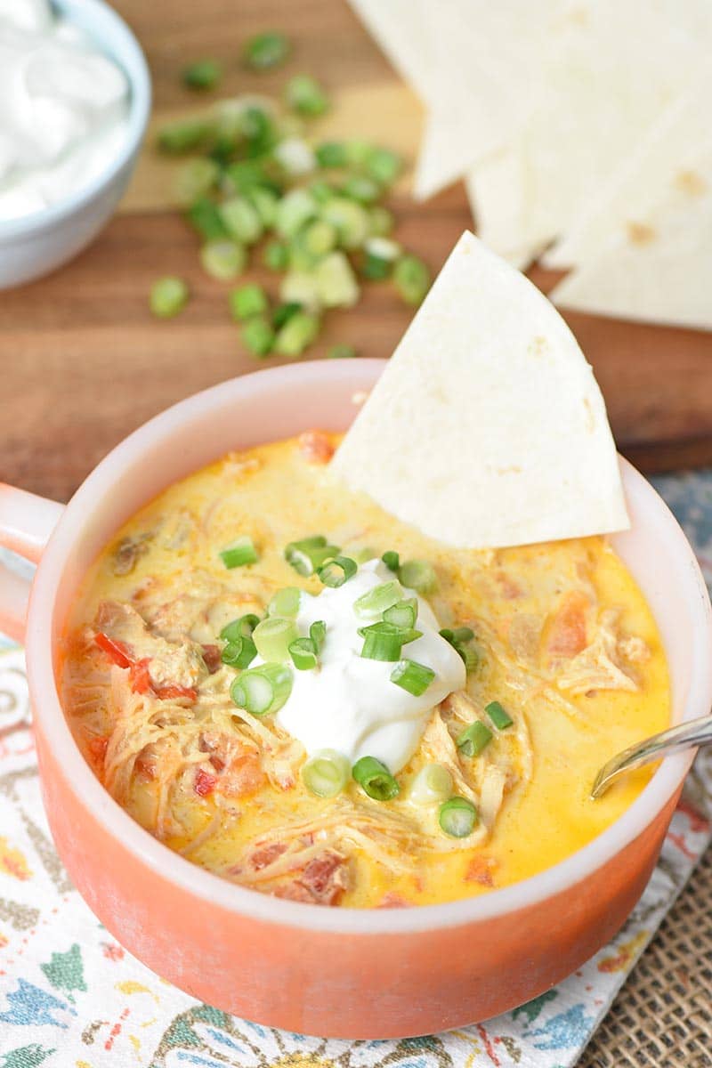 orange Fire-King soup bowl with chicken enchilada soup, tortilla triangle, sour cream, and green onions