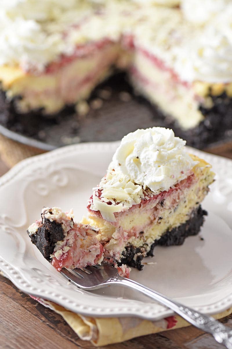 fork with bite of raspberry cheesecake on white plate