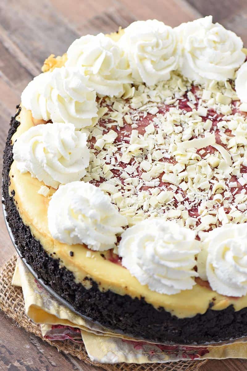 whole white chocolate raspberry cheesecake with Oreo cookie crust on wood countertop