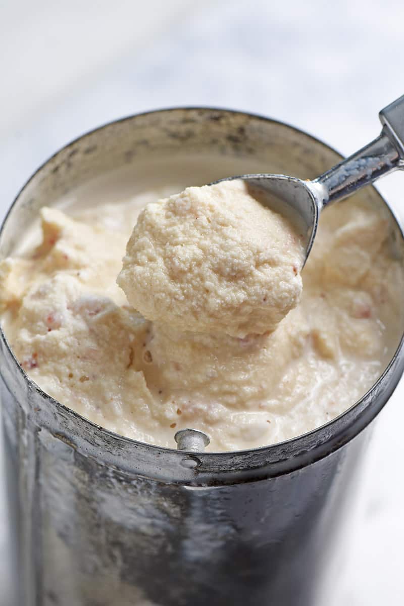 scoop of homemade strawberry ice cream in a metal canister