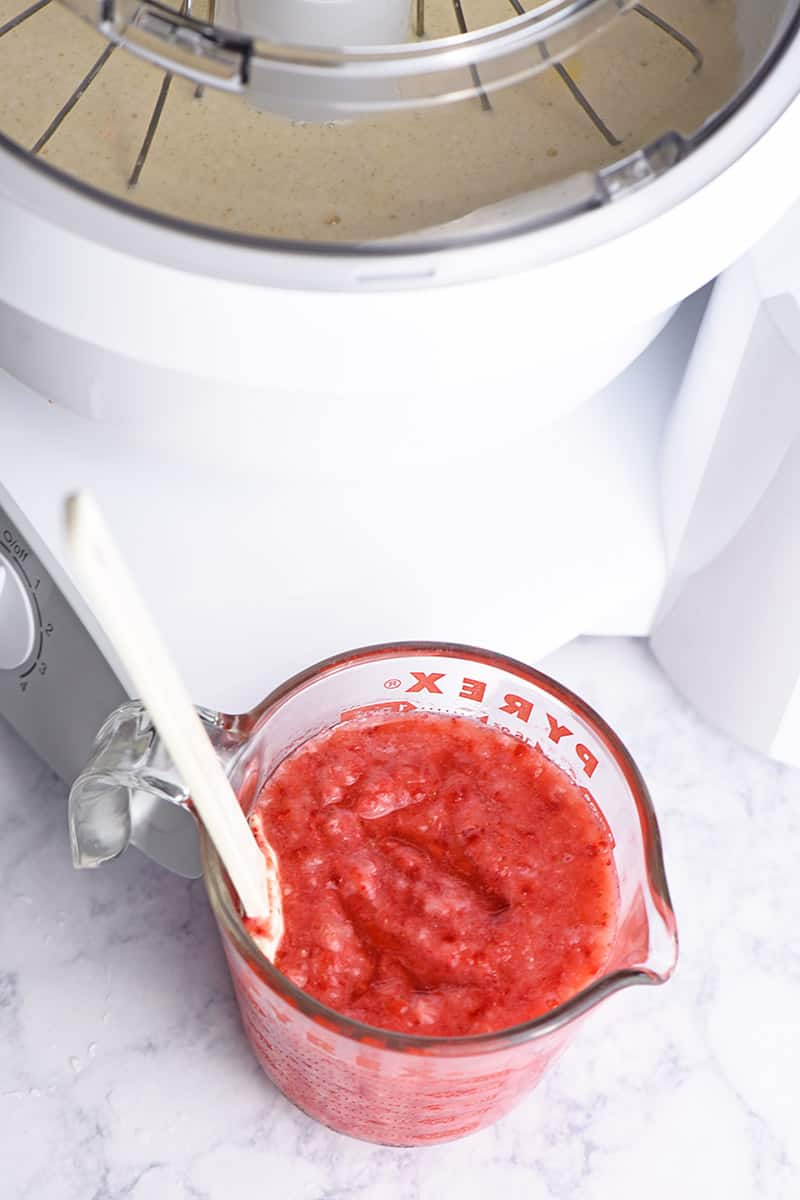 crushed strawberries for homemade ice cream recipe, in glass measuring cup next to Bosch mixer