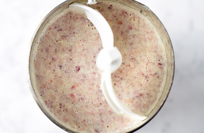 homemade strawberry ice cream mixture in metal canister with churning paddle