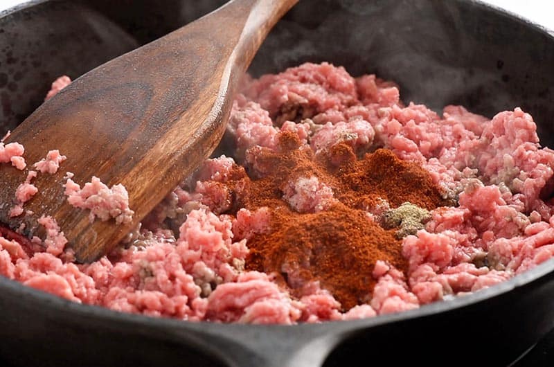 cooking ground beef and seasoning for tacos in cast iron skillet