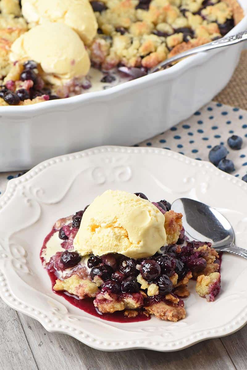 helping of blueberry cobbler with vanilla ice cream on a white pioneer woman plate