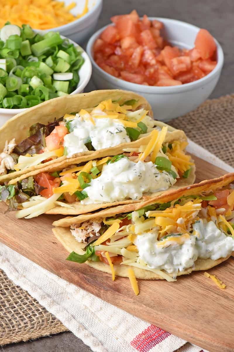 fish tacos with a tzatziki fish taco sauce on a wooden cutting board