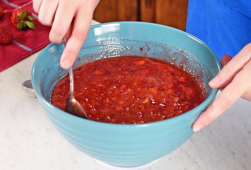 mixing together sugar, pectin, and crushed strawberries for freezer jam