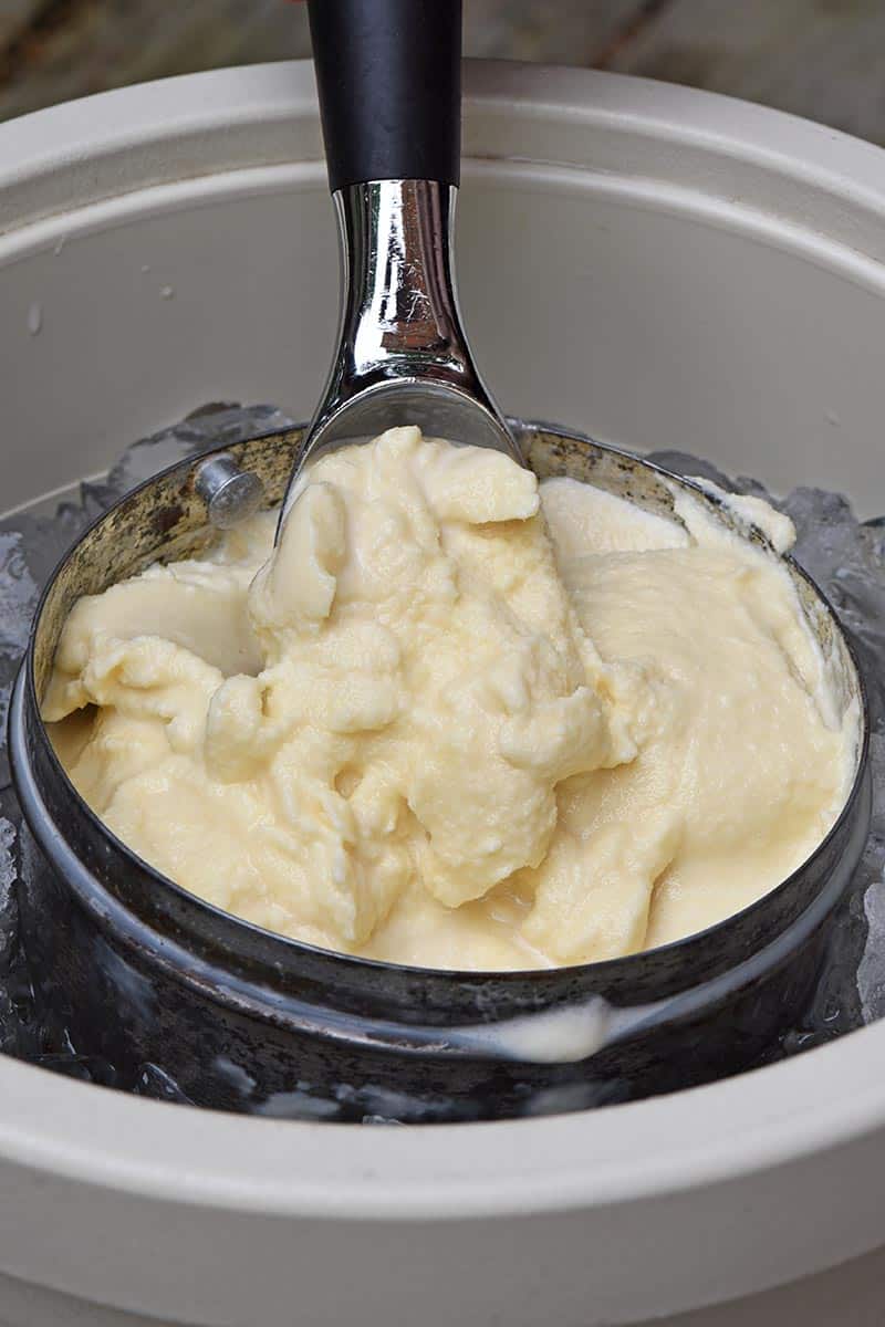 scooping old fashioned homemade vanilla ice cream out of an ice cream maker