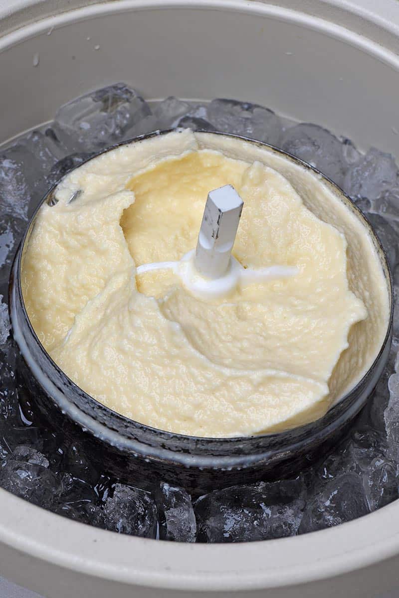 creamy old fashioned vanilla ice cream in metal canister of ice cream maker set in ice
