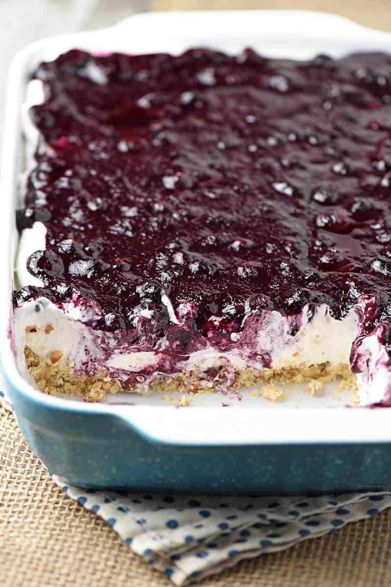 dreamy no bake blueberry dessert, aka blueberry yum yum recipe, in turquoise baking dish on burlap kitchen linen