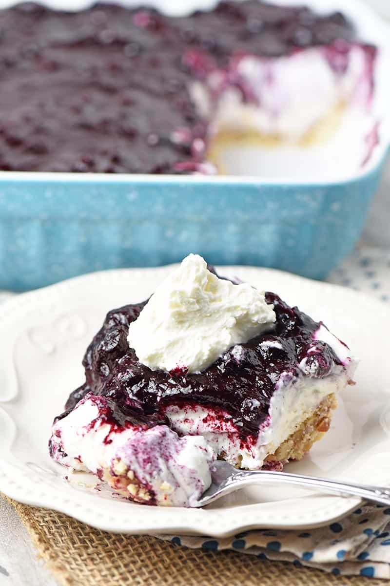 slice of creamy no bake blueberry yum yum recipe on white plate