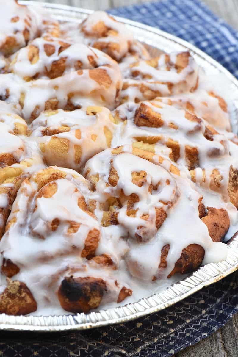 Dutch oven cinnamon rolls made with Pioneer mix, baked in foil pan and drizzled with powdered sugar icing