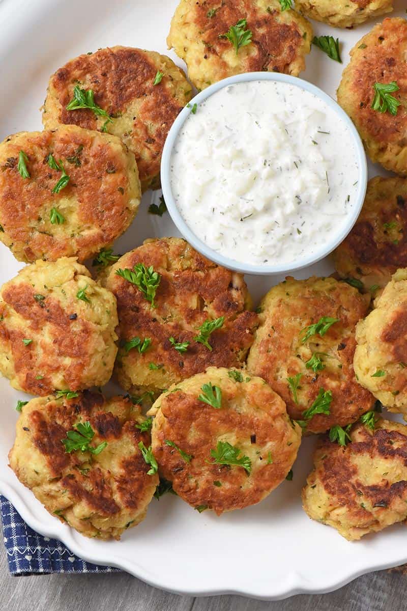 easy salmon cakes on white platter, served with homemade tzatziki sauce