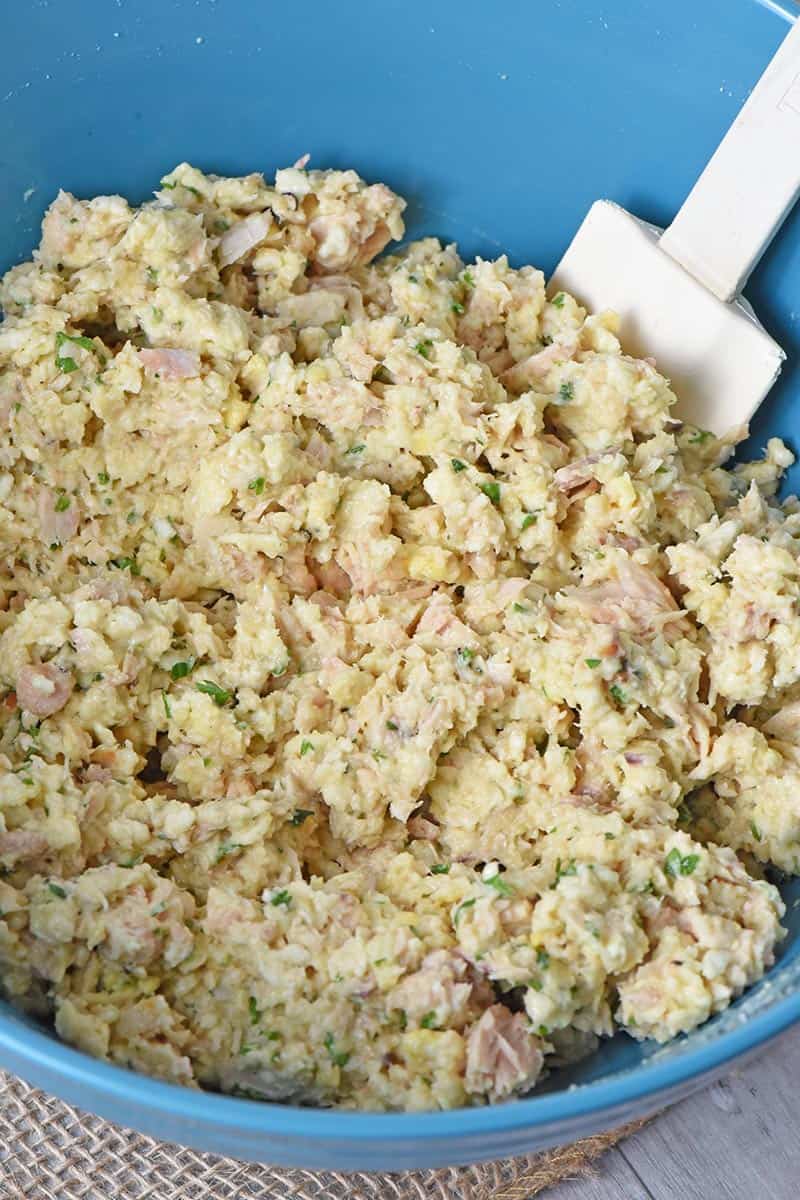 ingredients for salmon cakes in large blue mixing bowl with spatula