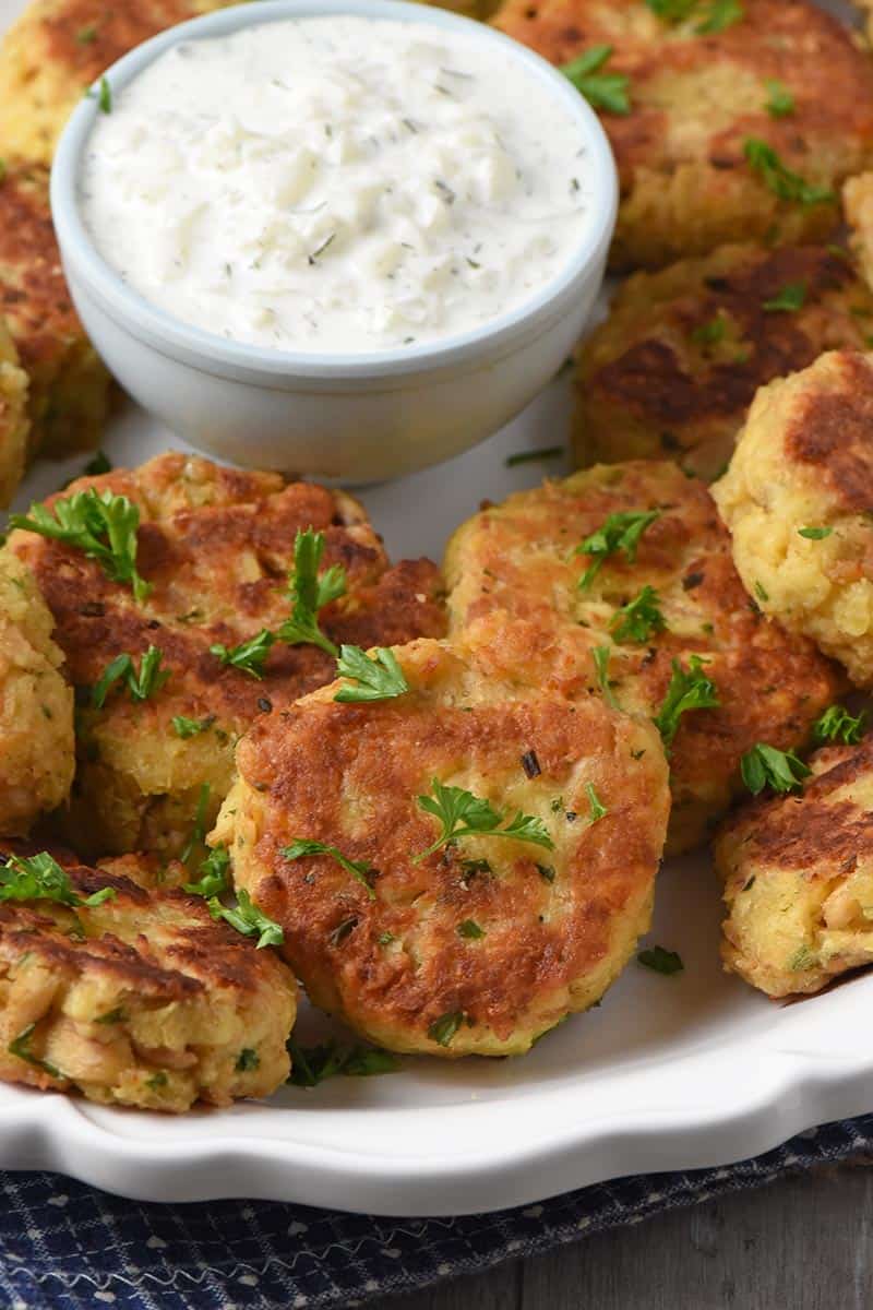 salmon patties served on white platter with tzatziki sauce