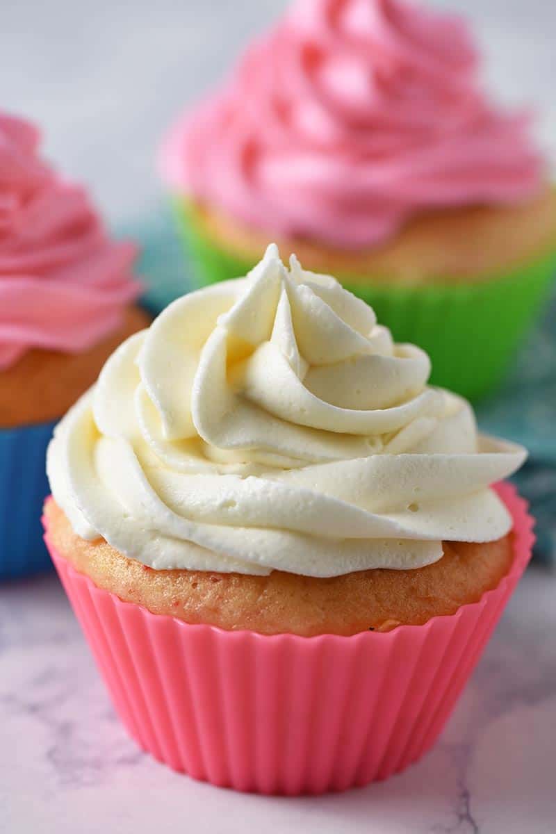 piping the best buttercream frosting onto cherry chip cupcakes