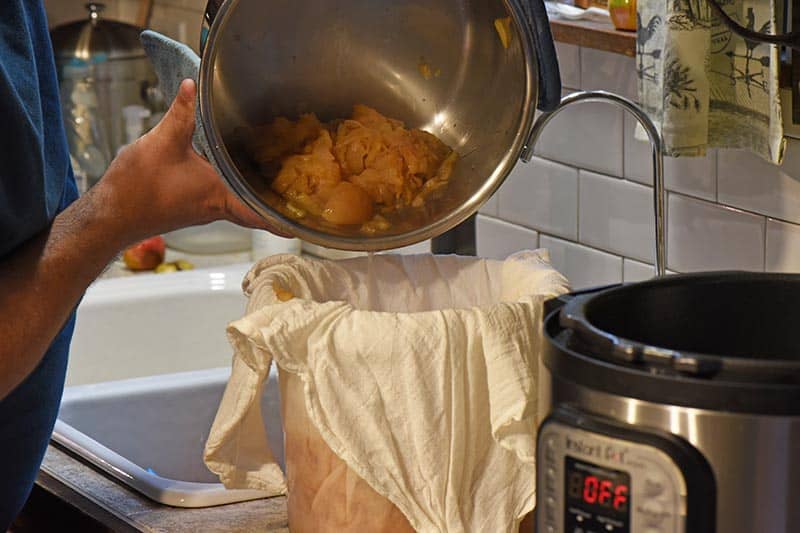 pouring apple juice and pulp into flour sack towel for straining