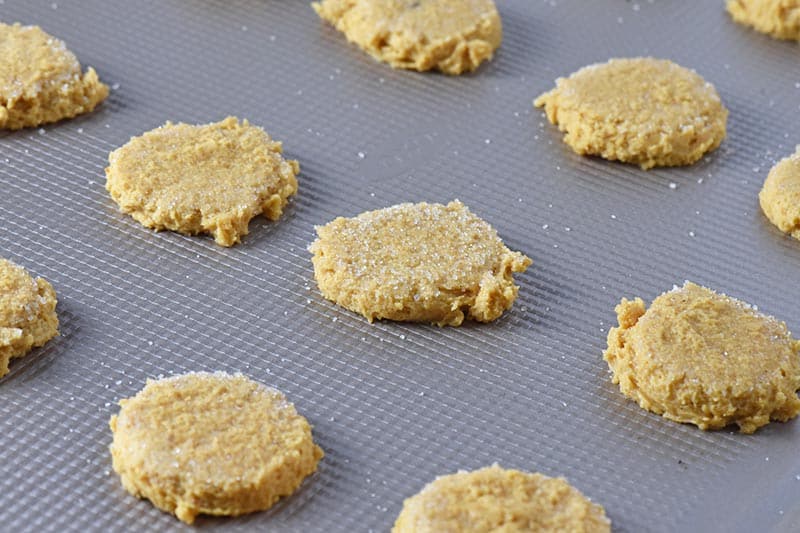 flattened pumpkin sugar cookies with sugar on top, ready to bake on ungreased baking sheet