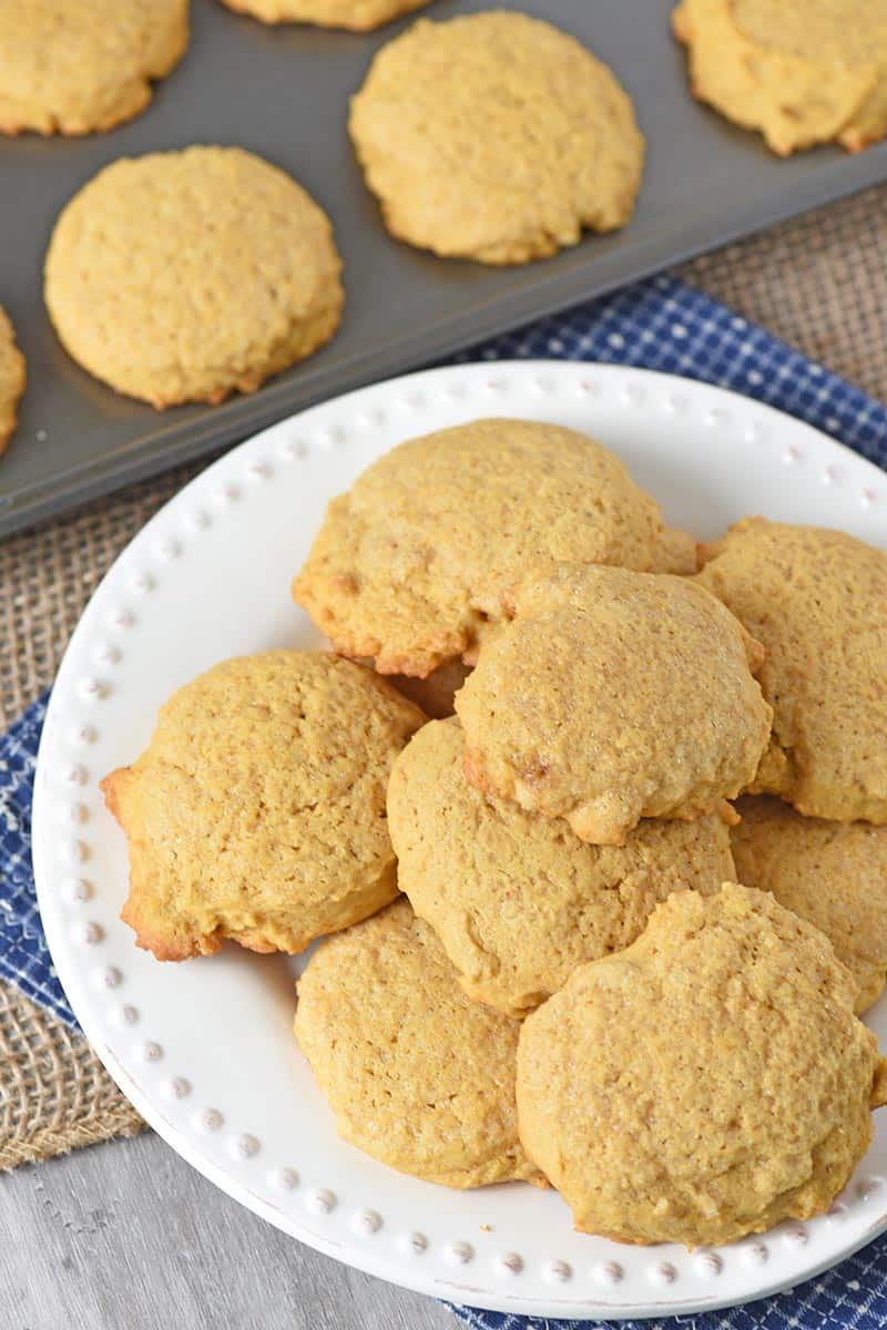 homemade pumpkin spice sugar cookies on a white plate with cookie sheet full of cookies