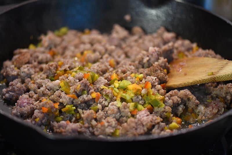cooking sausage and peppers in a cast iron skillet