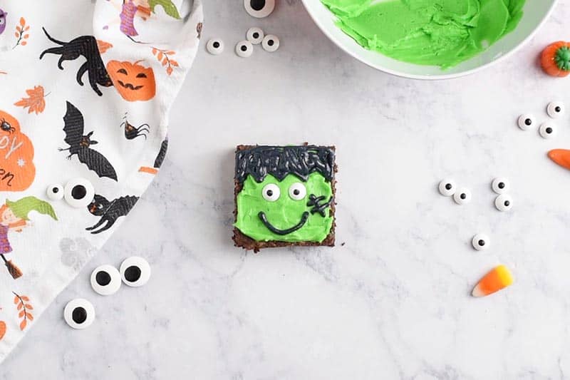 decoraed Frankenstein brownie with candy eyeballs, black icing smile, and stitches